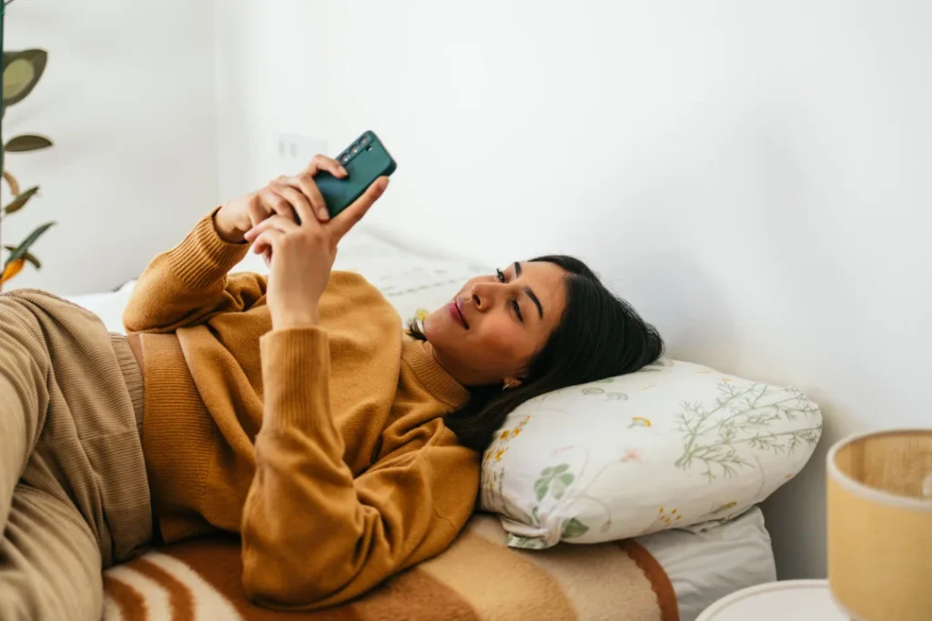 young woman lying on bed at home using smartphone 2026 02 28 20 43 07 utc | Voyager Recovery Center