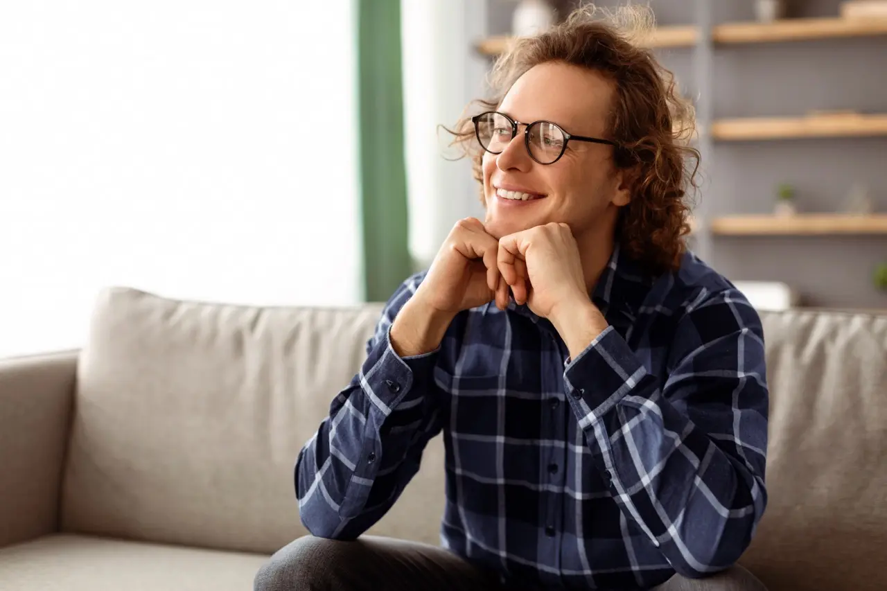man smiles thoughtfully relaxing on sofa indoors 2026 03 24 02 19 05 utc Large | Voyager Recovery Center