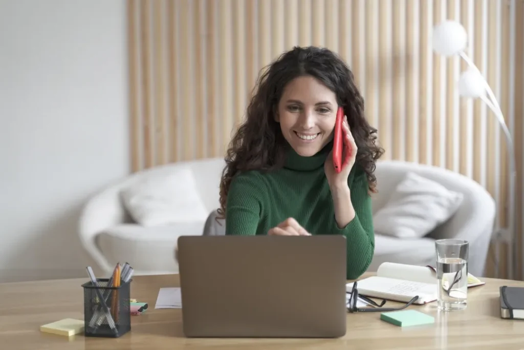 smiling woman talking on smartphone while using | Voyager Recovery Center