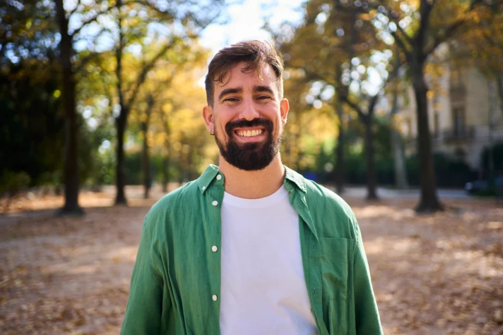 smiling man in green shirt standing in autumn park | Voyager Recovery Center